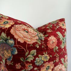 a red floral pillow sitting on top of a white wall