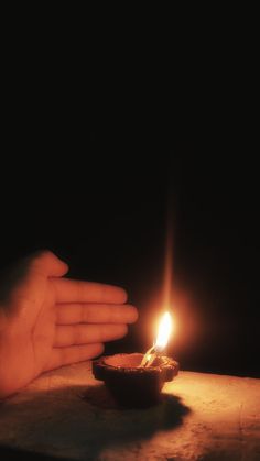 a person holding their hand over a lit candle