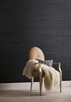 a chair with some fur on it in front of a black wall and white floor