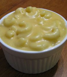 a white bowl filled with macaroni and cheese on top of a wooden table