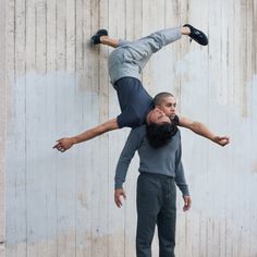 a man is doing a handstand on another man's head