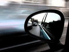 a car's side view mirror is shown with blurry images in the background