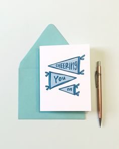 a greeting card with the words cheers you on it next to a pen and envelope