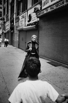 a black and white photo of a man dressed as darth vader walking down the street