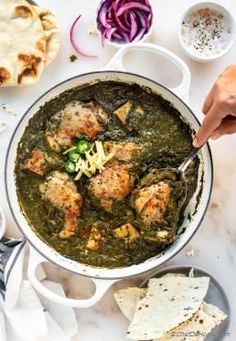 a bowl filled with meat and spinach next to pita bread