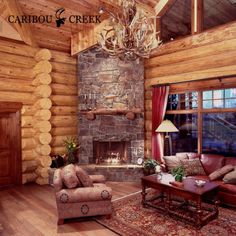 the living room is decorated in rustic wood and features a stone fireplace with antlers on it