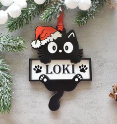 a black and white cat ornament hanging from a christmas tree with snowflakes