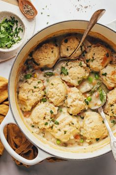 a pot filled with chicken and dumplings next to crackers on top of a table