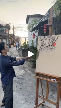 a man standing in front of an easel holding a paintbrush and drawing on it