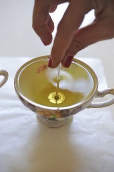 a person is dipping something into a small cup with liquid in the bottom and gold rim