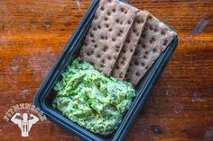 a container filled with crackers and green dip