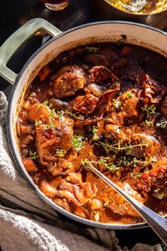 a pot filled with meat and vegetables on top of a table next to other dishes