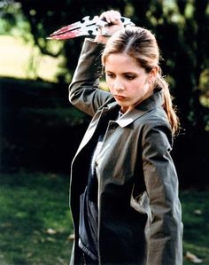 a young woman holding a pair of scissors on her head while standing in the grass