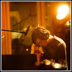 a man with headphones on sitting in front of a microphone and playing the piano