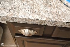 a granite counter top in a kitchen with stainless steel handles and knobs on it