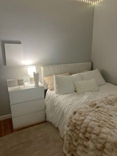 a bedroom with a bed, night stand and lamp in the corner next to it