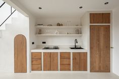 a kitchen with wooden cabinets and white counter tops next to an open staircase leading up to the second floor