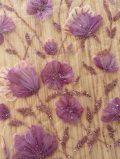 purple flowers are on a table cloth with beads and sequins in the center