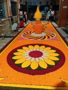 a large carpet with flowers on it in the middle of a building lobby, surrounded by people