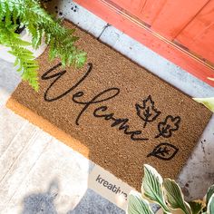 a welcome mat on the ground next to a potted plant