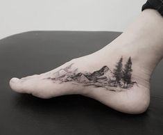 a person's foot with mountains and trees on it