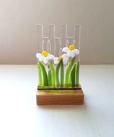 four glass vases with flowers in them on a wooden stand against a white wall