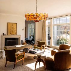 a living room filled with furniture and a chandelier hanging over the fire place