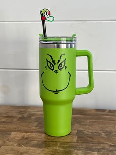 a green mug with a grin face drawn on the side and a toothbrush sticking out of it