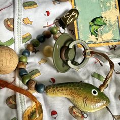 an assortment of toys and beads on a table cloth with a book in the background