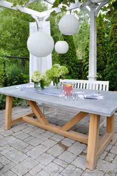 an outdoor dining table with white lanterns hanging from it