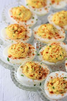 deviled eggs with sprinkles and seasoning in them on a glass platter