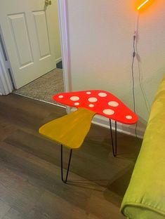 a red and yellow table sitting on top of a wooden floor next to a green couch