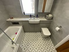 a bathroom with a sink, toilet and bathtub next to a window in the corner