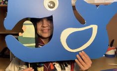 a woman holding up a cut out of a blue whale