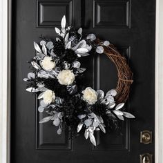 a black door with a wreath and flowers on it