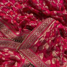 red and gold brocaded fabric with intricate designs on the border, as seen from above