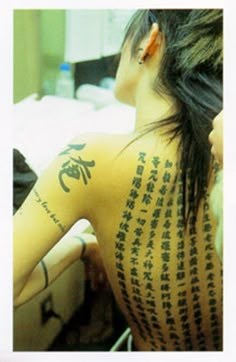 a woman with chinese writing on her back and arm tattooing it's upper half