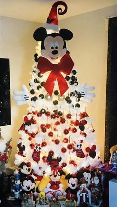 a mickey mouse christmas tree with lights and decorations on the top is decorated in red, white and black