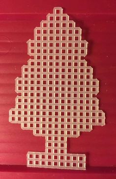 a cross stitch christmas tree ornament is shown on a red background with white squares