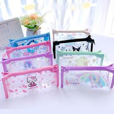 four hello kitty pencil cases sitting on top of a white table next to a potted plant