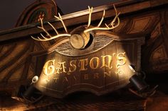 the sign for gaston's tavern is lit up at night with deer antlers on it