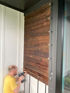 a man is painting the side of a building with wood planks on it's sides