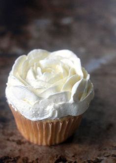 a cupcake with white frosting sitting on a table