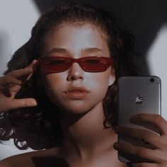 a woman wearing red sunglasses holding an iphone