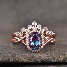 a ring with an oval shaped purple stone surrounded by smaller white diamonds on a rock