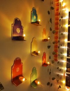 some lights are hanging on the wall next to each other and there is a shelf with candles in it