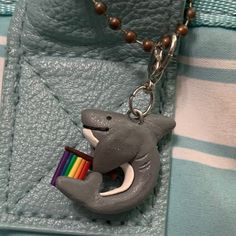 a necklace with a cat holding a rainbow pencil in it's mouth