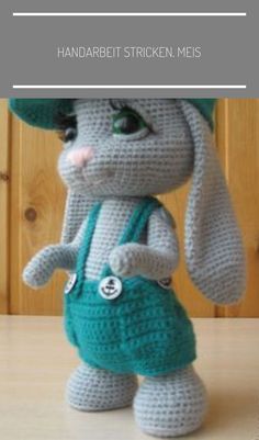 a crocheted stuffed animal wearing a green hat and holding a blue handbag