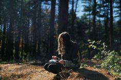 a person sitting in the woods writing on a piece of paper while looking at something