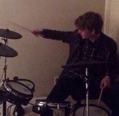 a man sitting in front of a drum set